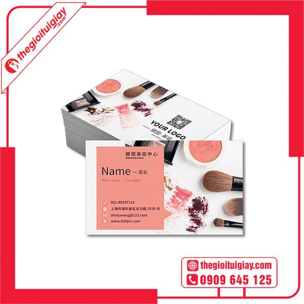 Cận cảnh một tấm name card màu đen mờ bằng giấy mỹ thuật, với logo và tên được ép kim màu vàng đồng lấp lánh