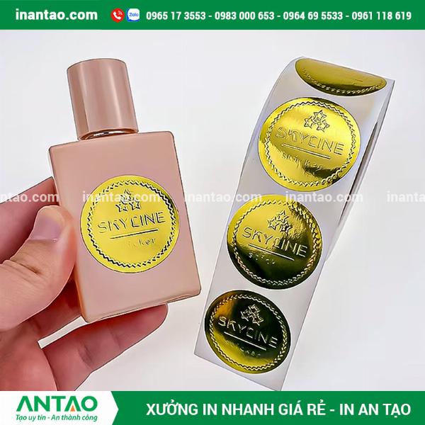 Cận cảnh tem nhãn decal xi bạc dán trên một hộp mỹ phẩm màu đen sang trọng, logo được dập nổi nhẹ